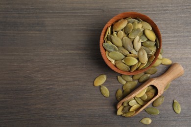 Photo of Bowl and scoop with pumpkin seeds on wooden table, flat lay. Space for text