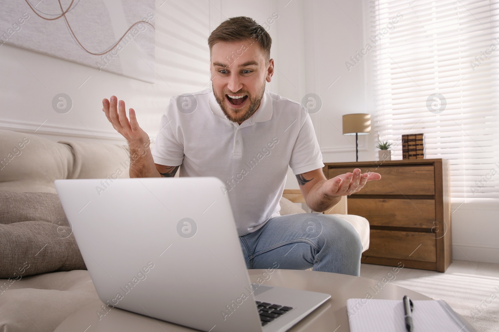 Photo of Emotional man participating in online auction using laptop at home