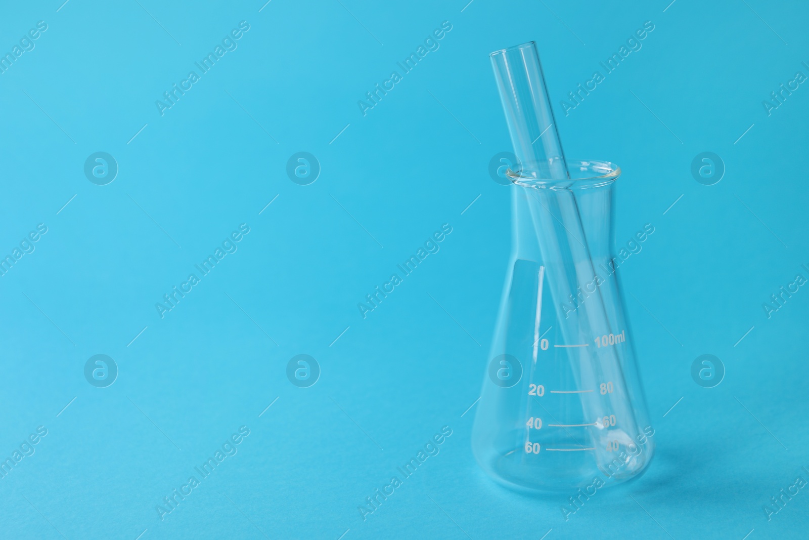 Photo of Flask with test tube on light blue background, space for text. Laboratory glassware