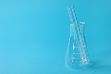 Flask with test tube on light blue background, space for text. Laboratory glassware