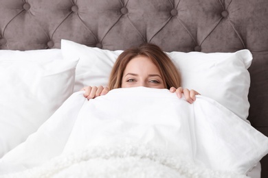 Photo of Young beautiful woman hiding under blanket in bed at home. Sleeping time