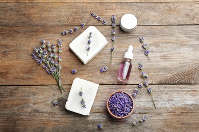 Flat lay composition of handmade soap bars with lavender flowers and ingredients on brown wooden background