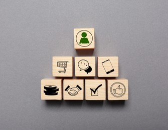 Image of Professional buyer. Wooden cubes with different icons on grey background, top view