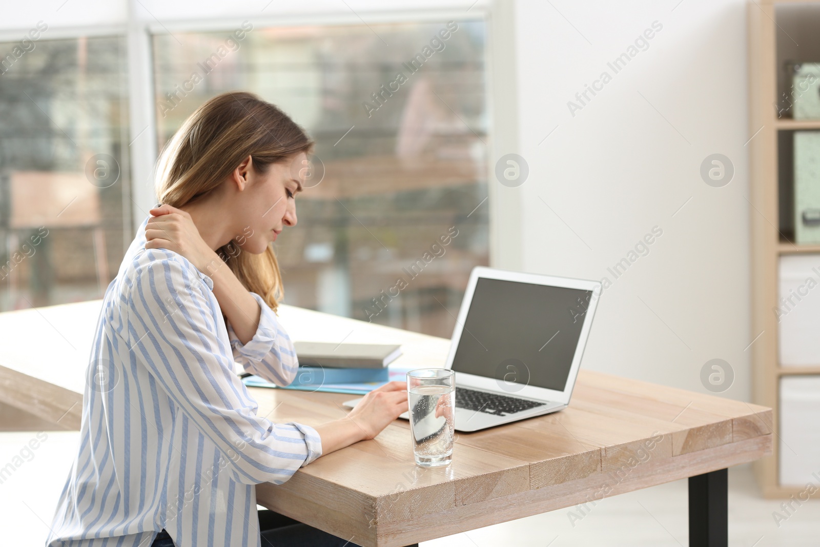 Photo of Woman suffering from neck pain in office. Symptom of bad posture