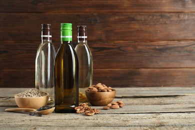 Photo of Vegetable fats. Different cooking oils in glass bottles and ingredients on wooden table, space for text