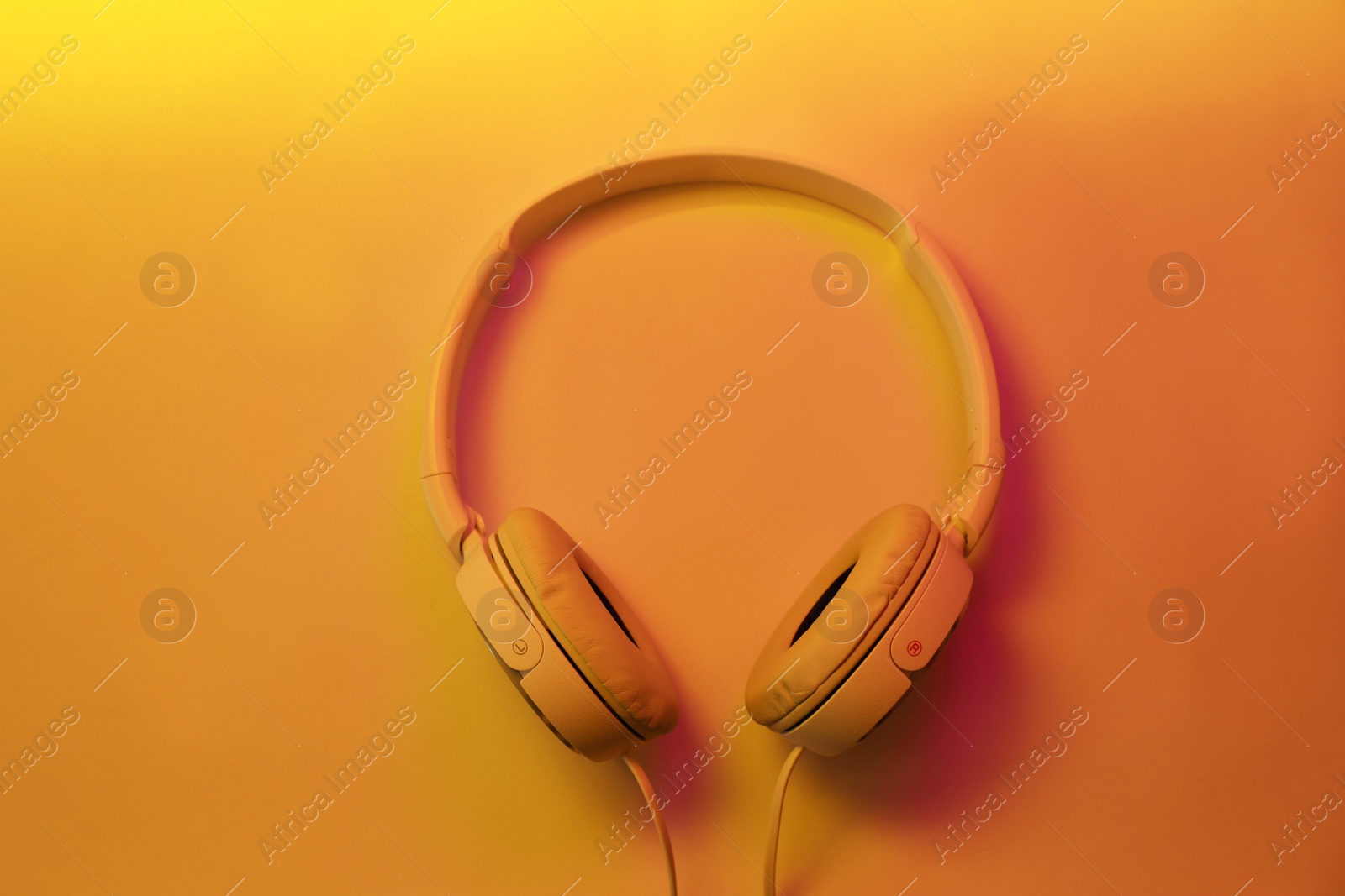 Photo of Stylish modern headphones with earmuffs on color background, top view