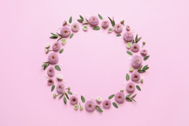 Photo of Wreath made of beautiful flowers and green leaves on pink background, flat lay. Space for text