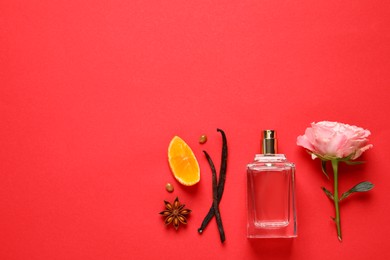 Flat lay composition with bottle of perfume and fresh citrus fruit on red background. Space for text