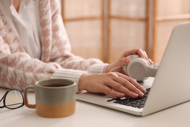 Woman with modern laptop learning at table indoors, closeup