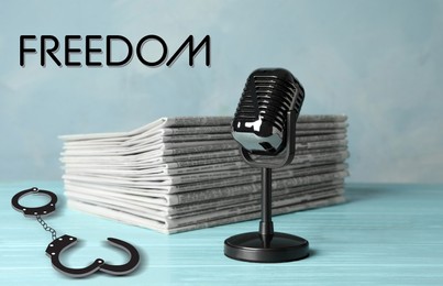 Freedom of speech. Newspapers, microphone and handcuffs on light blue wooden table