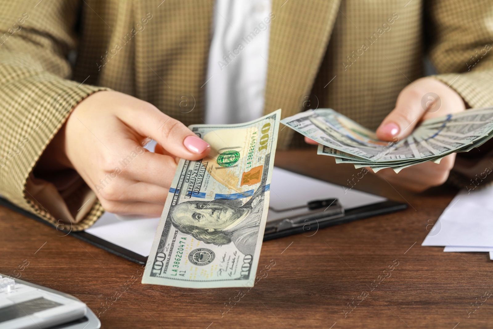 Photo of Woman holding dollar banknotes at wooden table, closeup. Money exchange concept