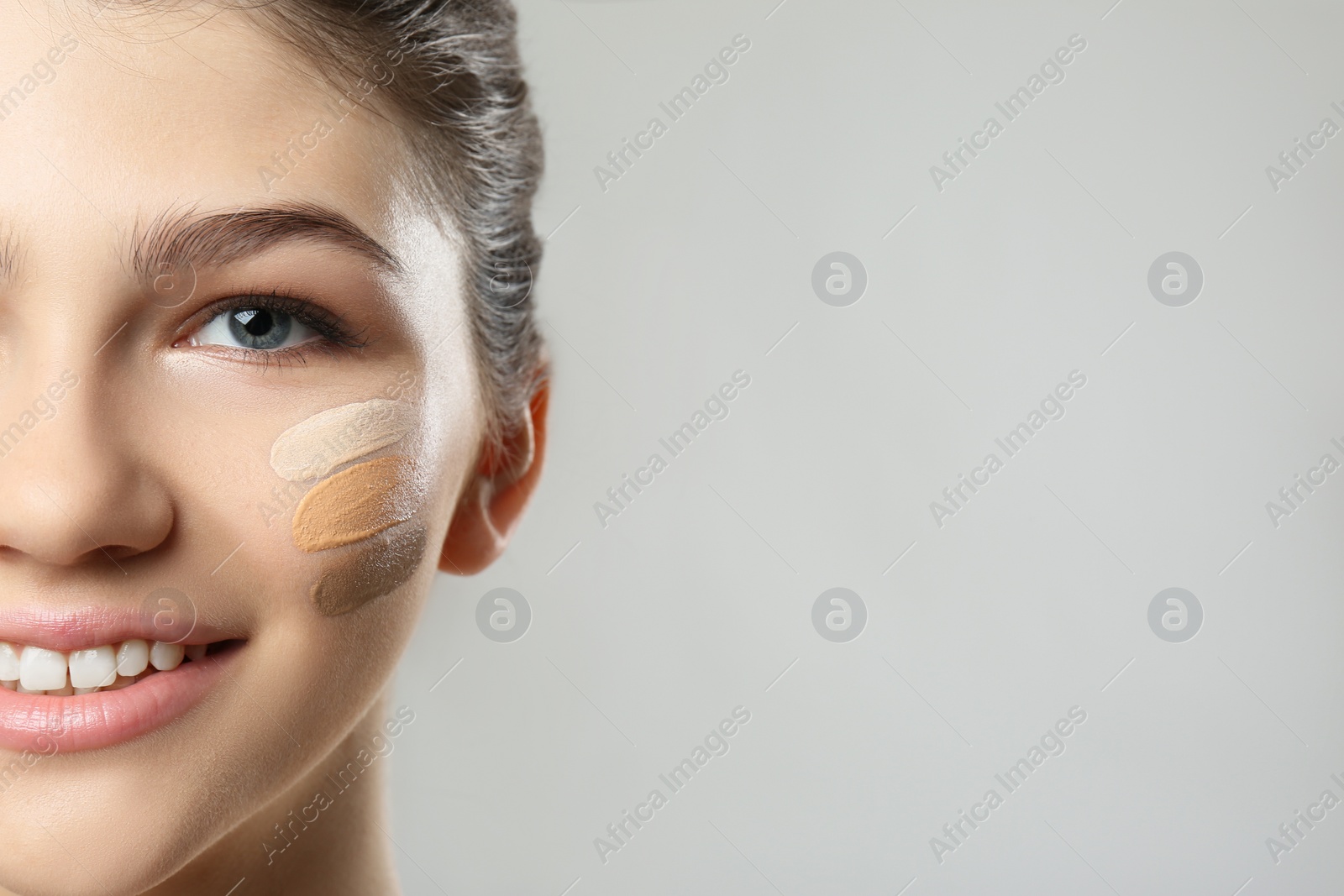 Photo of Beautiful girl on light grey background, closeup. Using concealers and foundation for face contouring