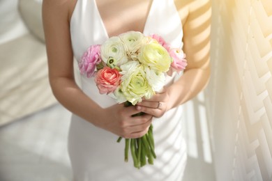 Photo of Bride with beautiful ranunculus bouquet indoors, closeup