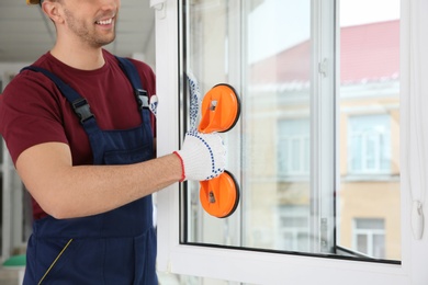 Construction worker using suction lifter during window installation indoors, closeup