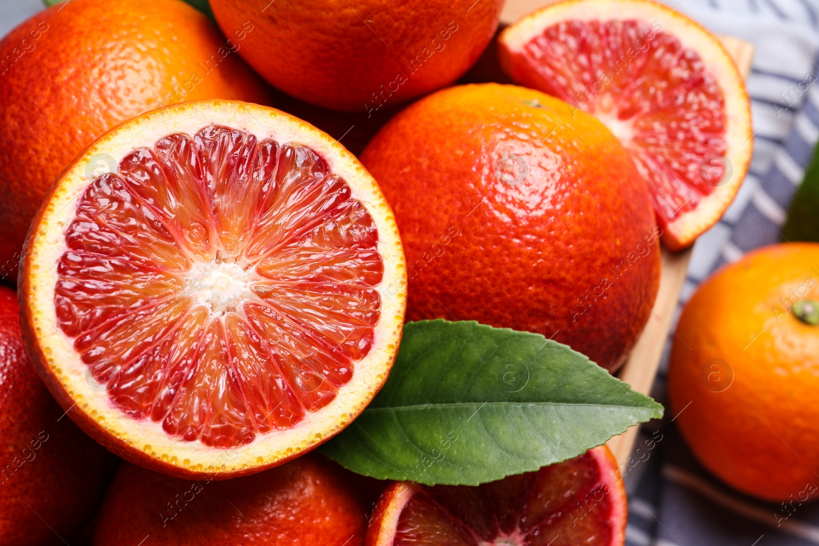 Photo of Whole and cut ripe red oranges with green leaf, closeup