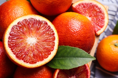 Photo of Whole and cut ripe red oranges with green leaf, closeup