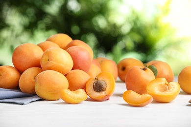 Delicious ripe sweet apricots on white table against blurred background