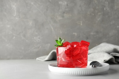 Photo of Delicious red jelly in glass on table. Space for text