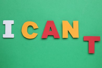 Motivation concept. Changing phrase from I Can't into I Can by removing paper letter T on green background, top view