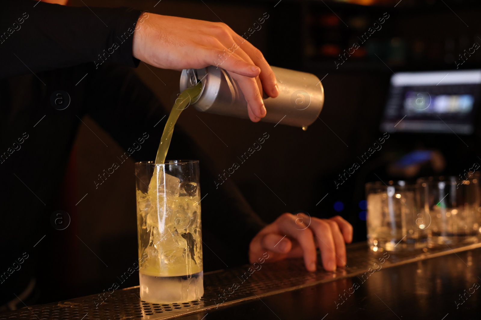 Photo of Bartender pouring energy drink into glass at counter in bar, closeup