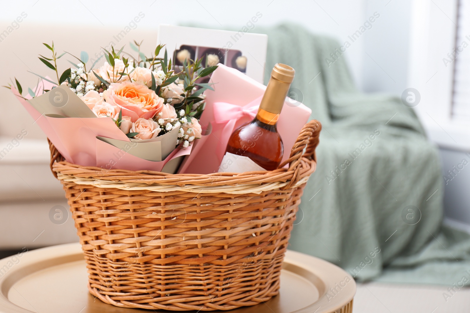 Photo of Wicker basket with gifts on table indoors