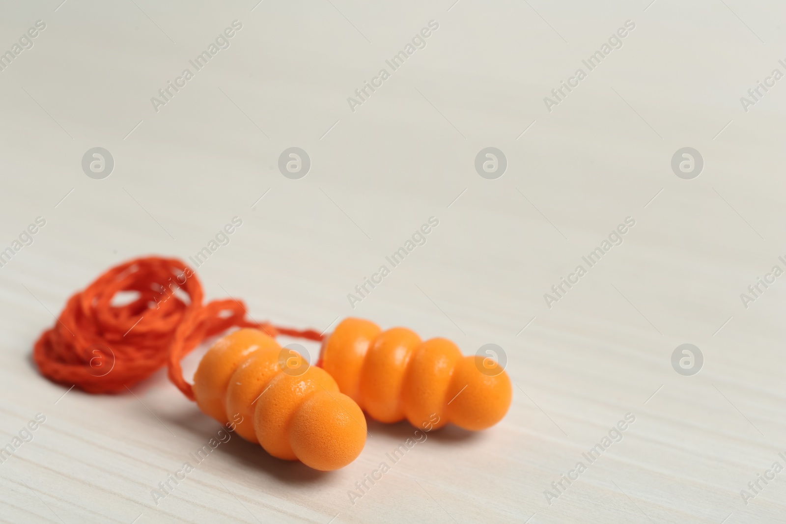 Photo of Pair of ear plugs on white wooden background, closeup. Space for text