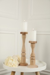 Photo of Elegant candlesticks with burning candles and flower on white table
