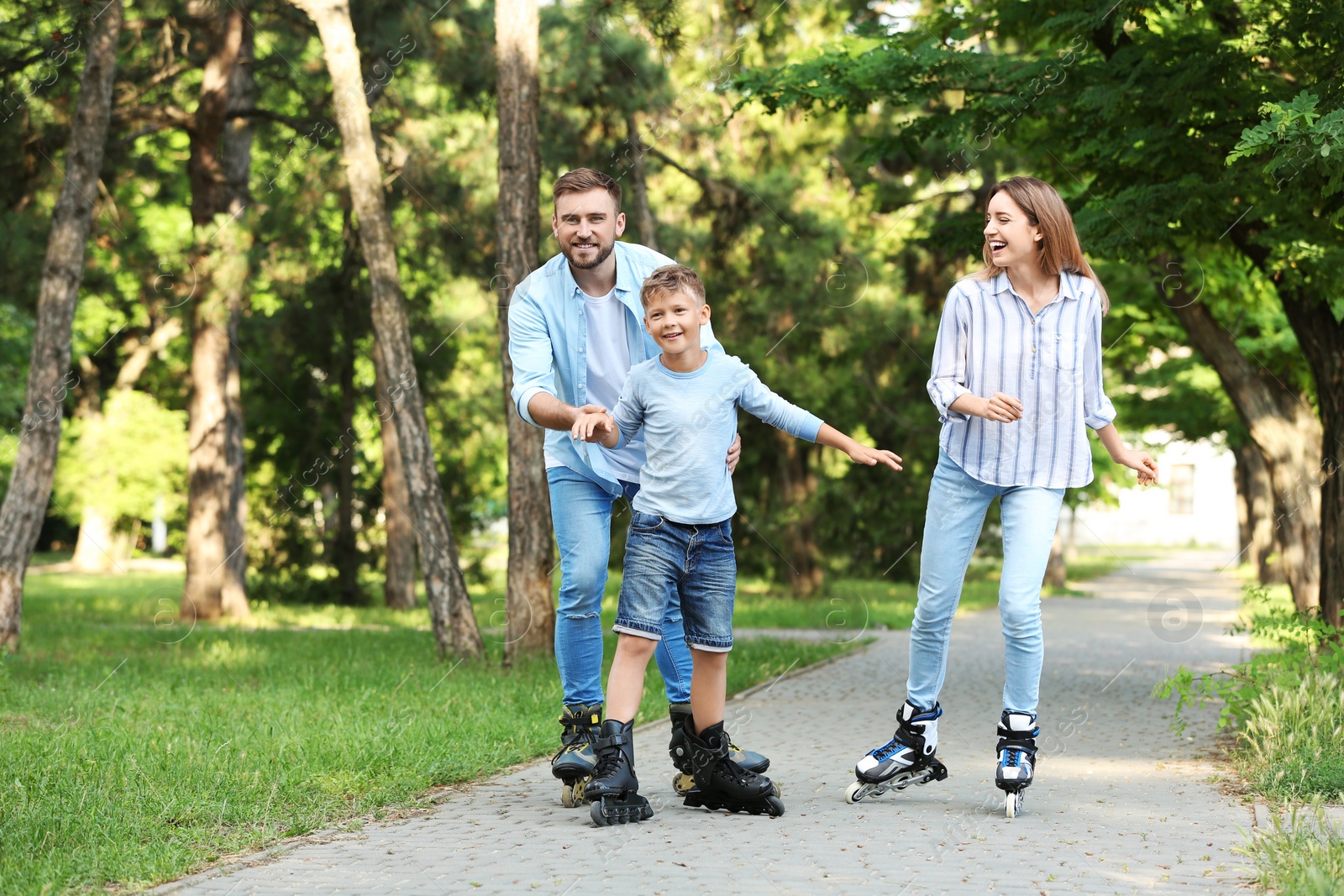 Photo of Young happy family roller skating in summer park