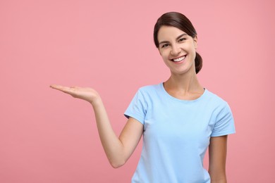 Photo of Special promotion. Happy woman showing something on pink background, space for text