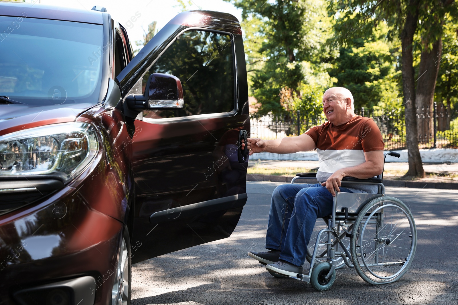 Photo of Senior man in wheelchair opening door of his van outdoors