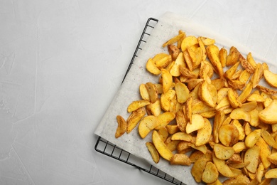 Photo of Cooling rack with delicious oven baked potatoes on grey background, top view. Space for text