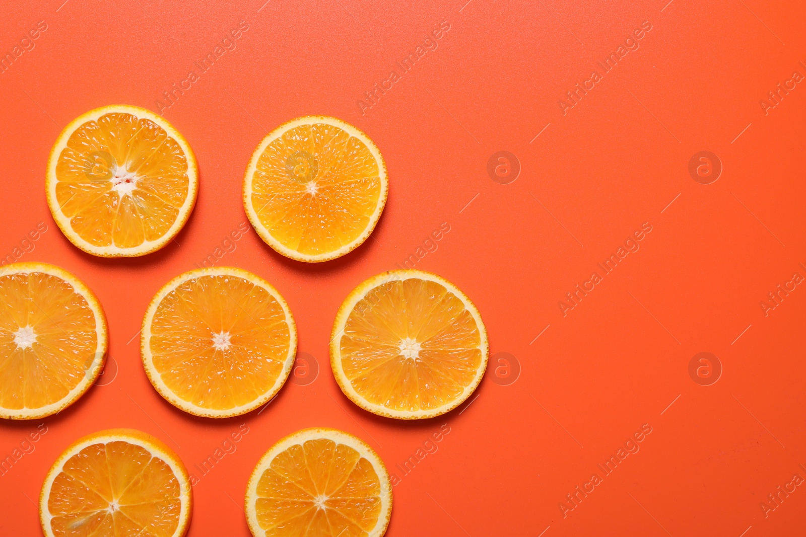 Photo of Slices of juicy orange on terracotta background, flat lay. Space for text