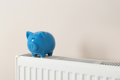 Photo of Piggy bank on heating radiator against light background