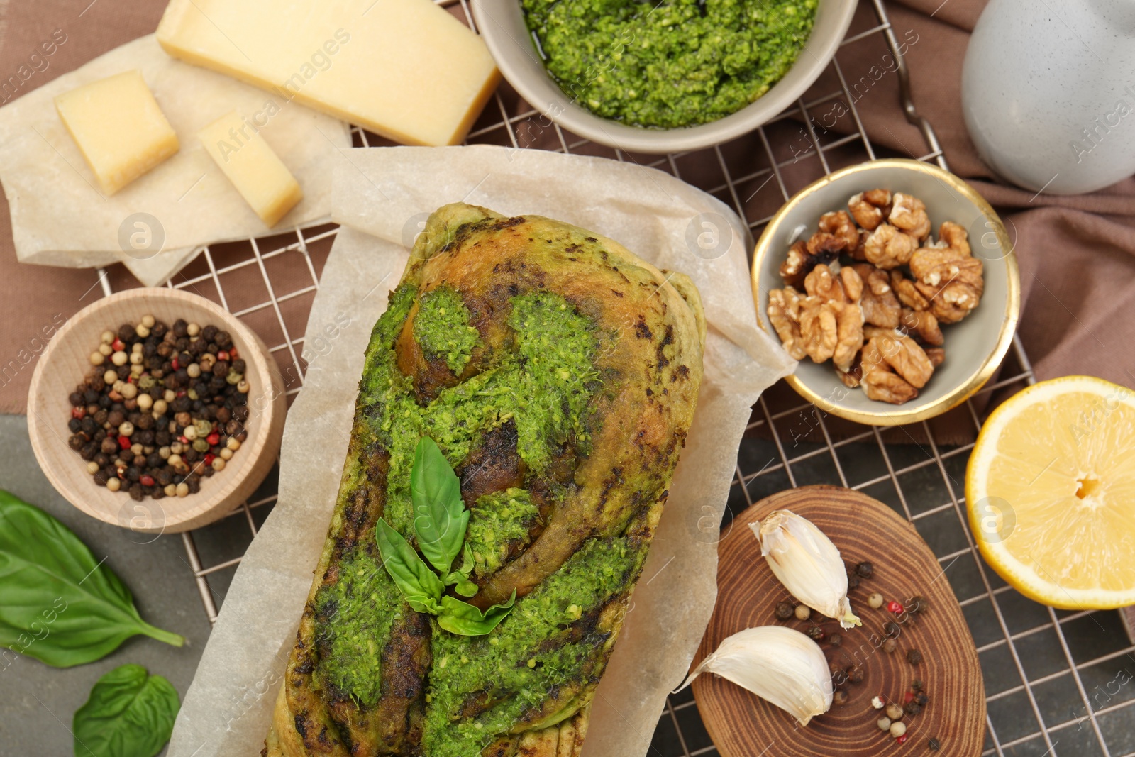 Photo of Freshly baked pesto bread with ingredients on table, flat lay