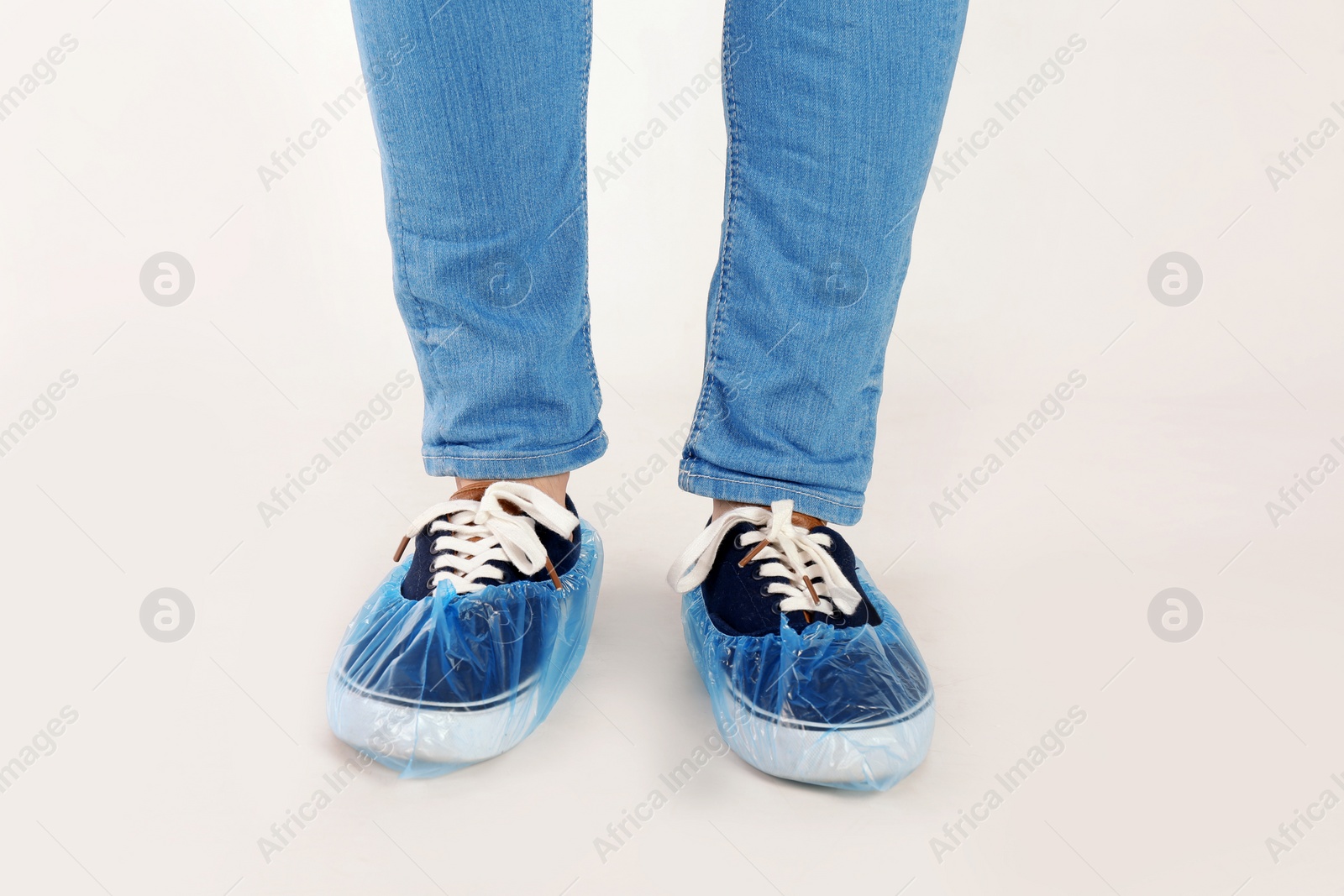 Photo of Man with blue shoe covers worn over sneakers on white background, closeup