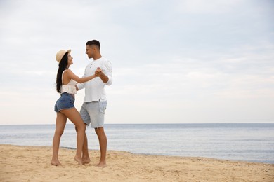 Photo of Lovely couple dancing on beach near sea. Space for text