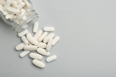 Vitamin pills and bottle on grey background, top view. Space for text