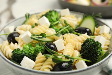 Photo of Bowl of delicious pasta with cucumber, olives, broccoli and cheese, closeup