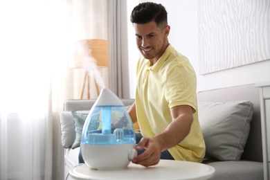 Man using modern air humidifier at home