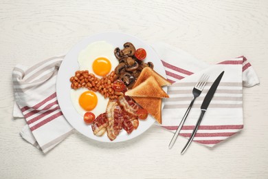 Plate with fried eggs, mushrooms, beans, tomatoes, bacon and toasts served on white wooden table, flat lay. Traditional English breakfast