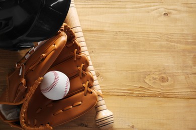 Baseball glove, bat, ball and batting helmet on wooden table, flat lay. Space for text