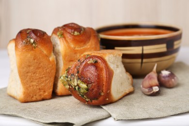 Photo of Delicious pampushky (buns with garlic) served for borsch on white table, closeup. Traditional Ukrainian cuisine