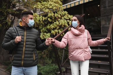 Photo of Couple in medical face masks walking outdoors. Personal protection during COVID-19 pandemic