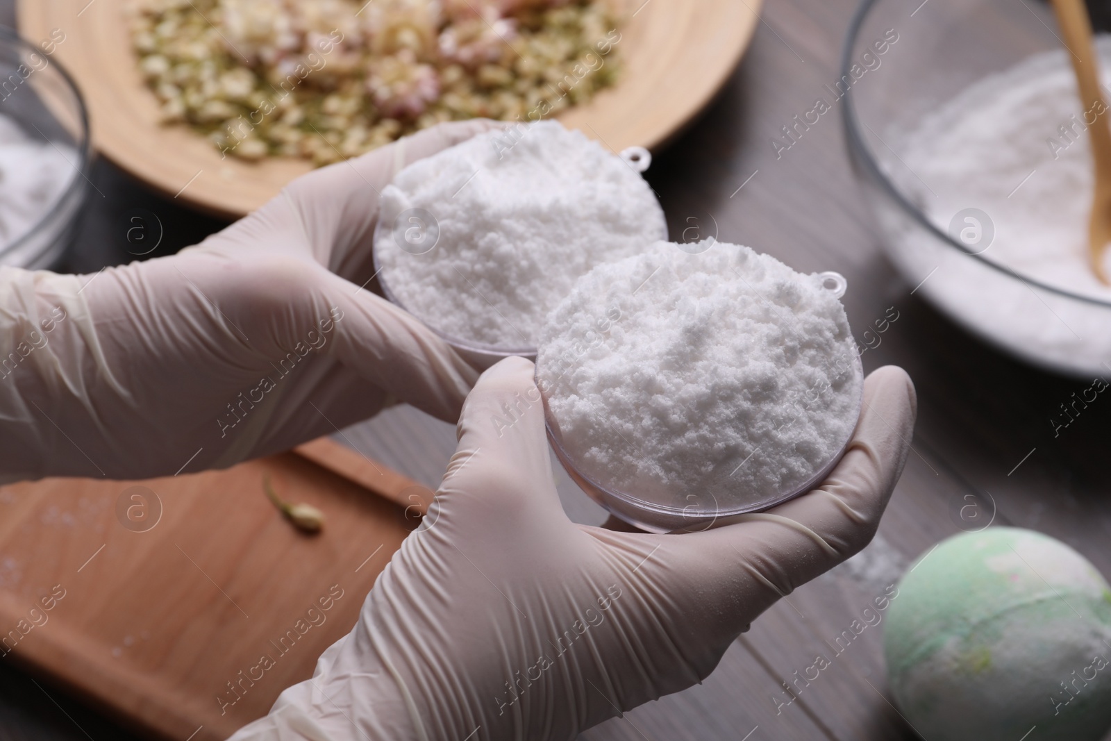 Photo of Woman in gloves making bath bomb at table, closeup