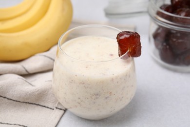 Glass of delicious date smoothie on white table, closeup
