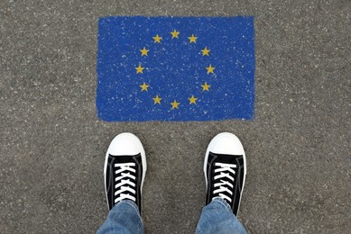 Image of Immigration. Man standing on asphalt near flag of European Union, top view