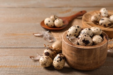 Photo of Bowl and quail eggs on wooden table. Space for text
