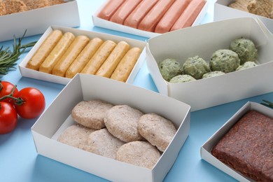 Photo of Many different raw vegan meat products on light blue background, closeup