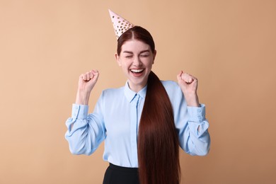 Photo of Happy woman in party hat on beige background