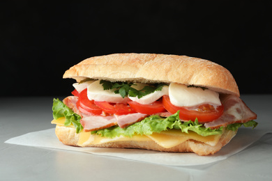 Photo of Delicious sandwich with fresh vegetables and mozzarella on grey table